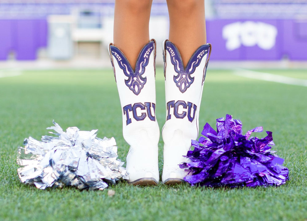 Las piernas de una corista de la TCU con sus botas posando para mostrar sus botas TCU personalizadas blancas y moradas.